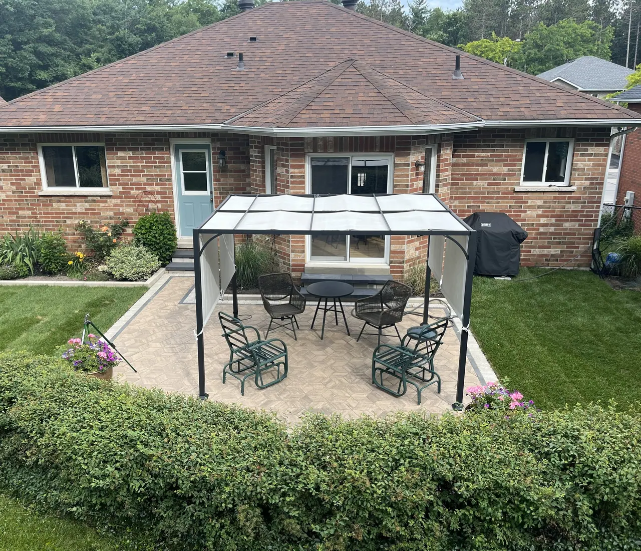 Interlocking paver patio with a gazebo-covered dining set behind a brick bungalow in Barrie, ON