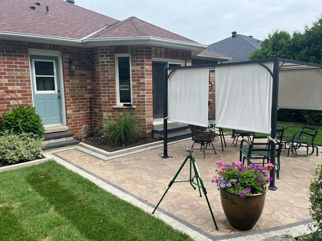 Paver patio and side entrance steps beside a brick bungalow in Barrie, ON, with planters and a gazebo