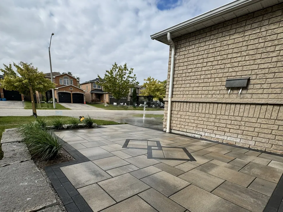 Slab patio with a dark border and a diamond inlay beside a brick home in Simcoe County, ON