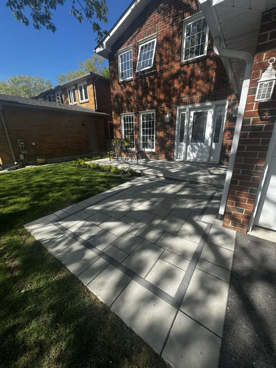 Large-format slab walkway with a dark border set into a front lawn in Barrie, ON