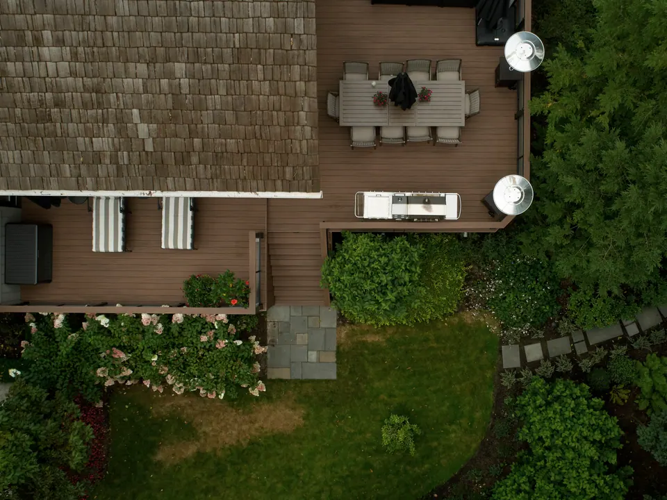 Aerial view of a backyard deck with a stepped landing and a stone walkway through garden beds in Simcoe County, ON