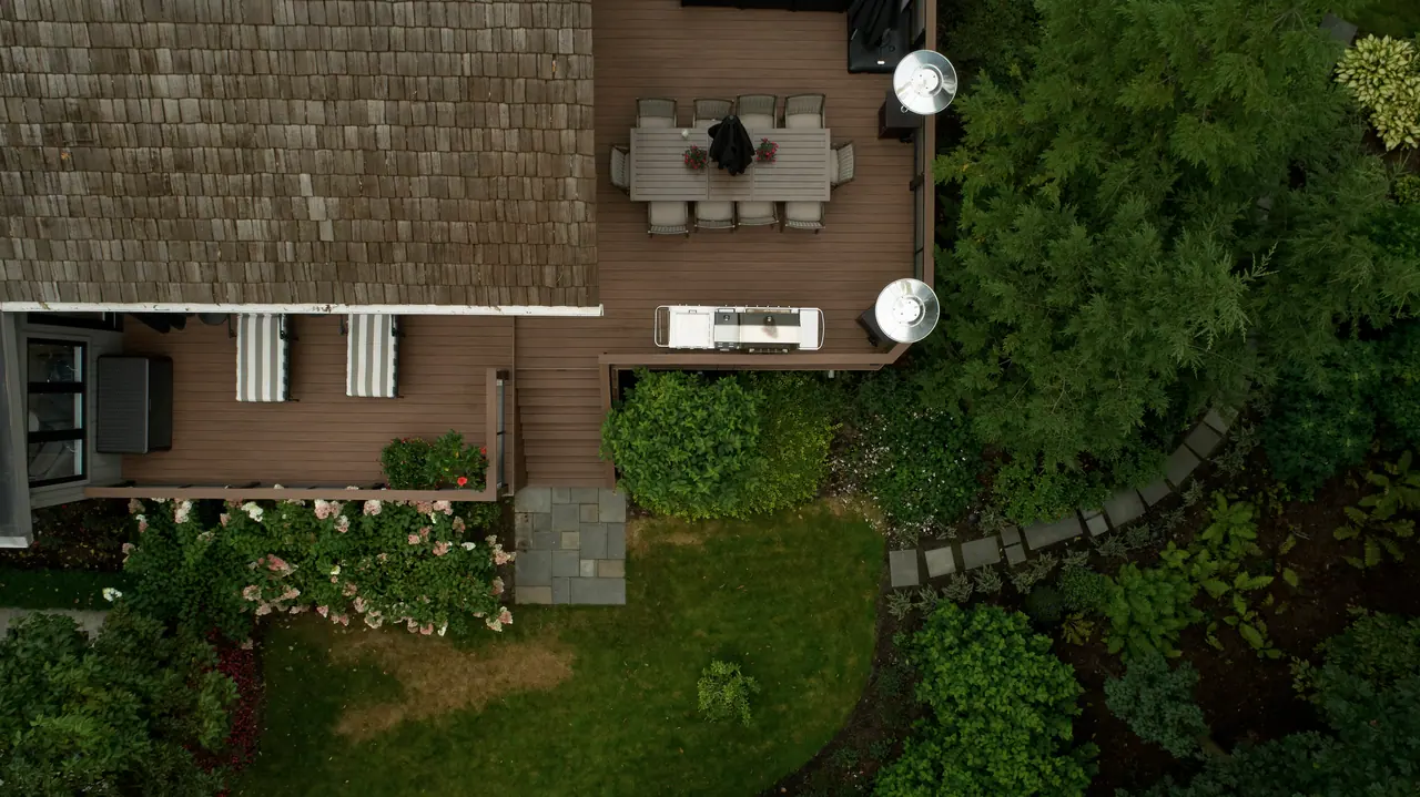 Aerial view of a backyard deck with a stepped landing and a stone walkway through garden beds in Simcoe County, ON