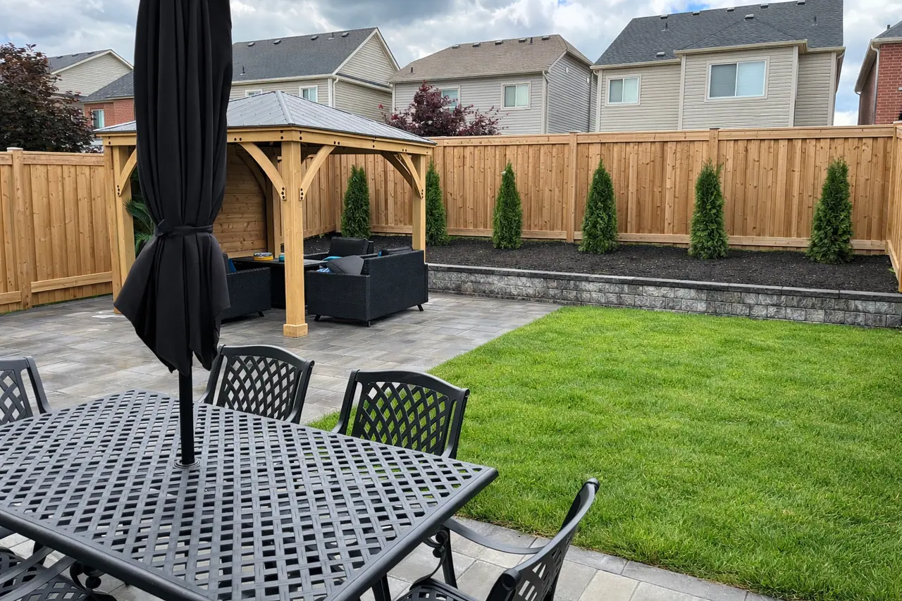 Slab patio with a cedar gazebo over a dining set, a low block wall and a new lawn in Simcoe County, ON