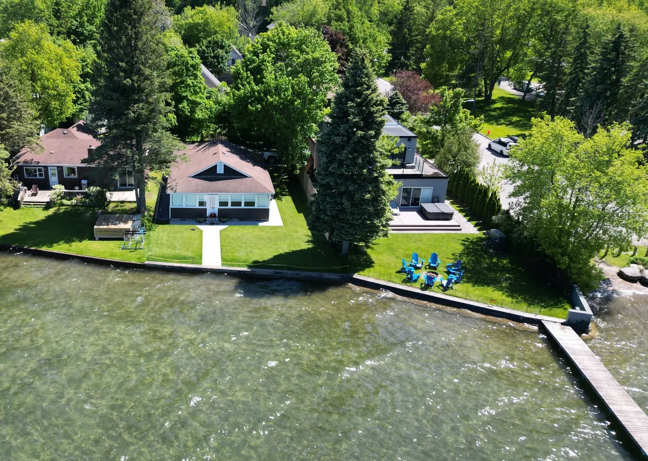 Aerial view of a waterfront backyard with a walkway to the shoreline and fire-pit seating in Simcoe County, ON