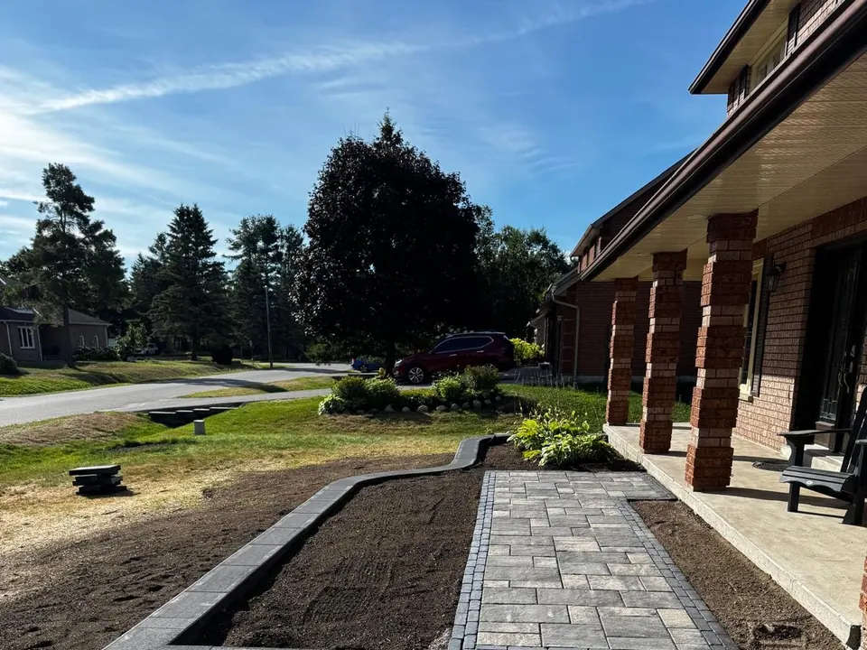 Paver walkway and front entrance between brick pillars with new planting beds in Midhurst, ON